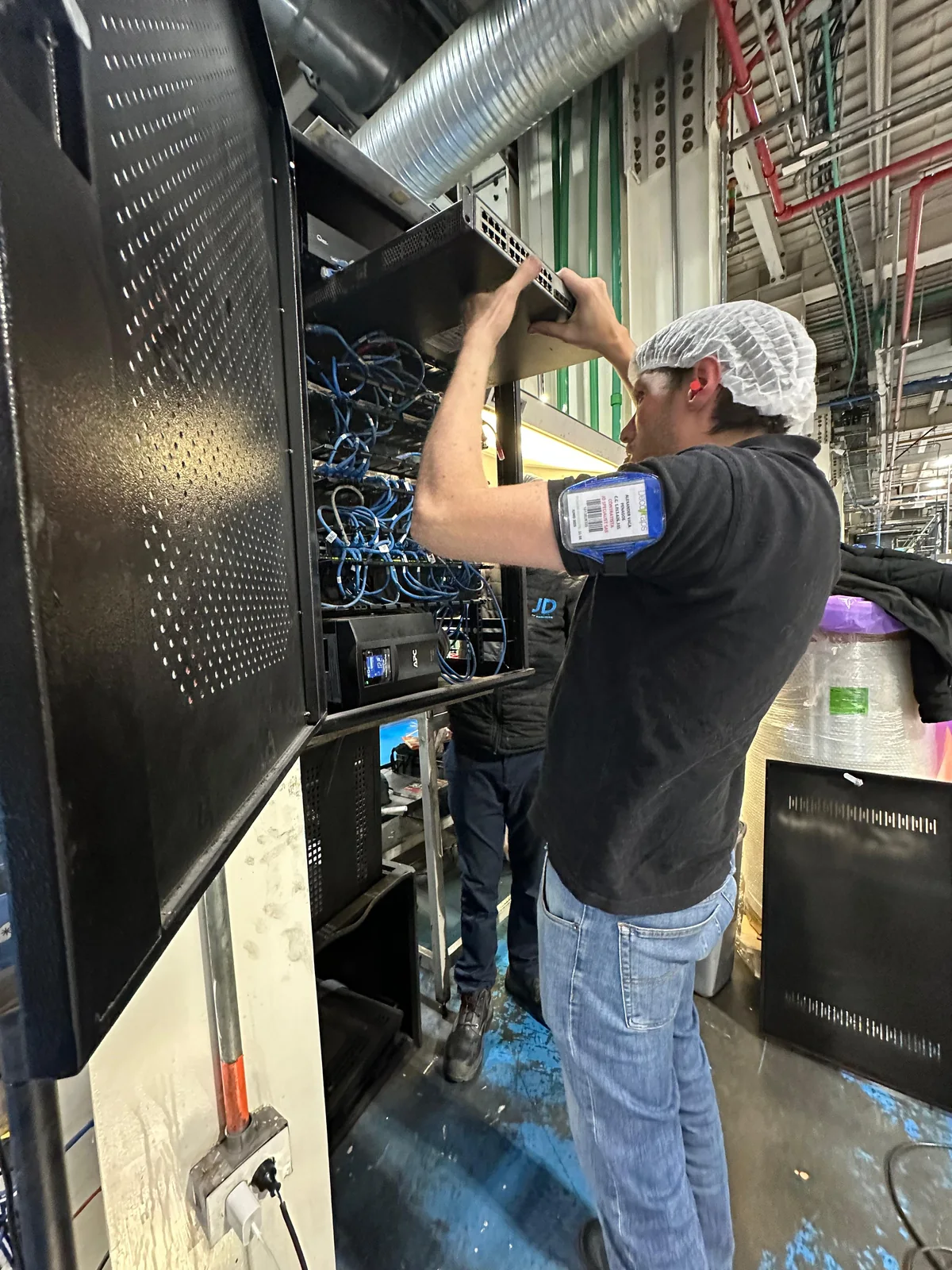 Técnico de JD SPECIALIST trabajando en un rack de comunicaciones.
